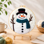 Finished snowman with teal scarf needle felting displayed on a wooden easel