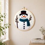 Snowman with teal scarf needle felt wall art displayed in a bright home interior
