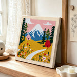 Snowy mountain and wildflowers punch needle artwork displayed on a table