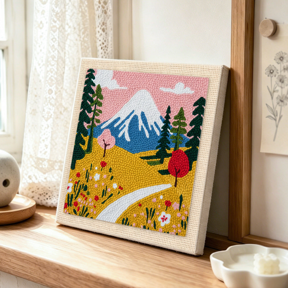 Snowy mountain and wildflowers punch needle artwork displayed on a table
