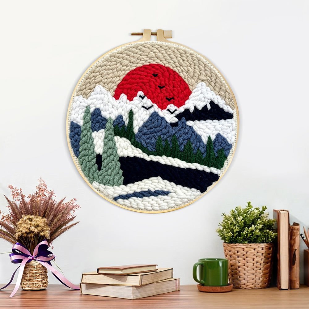 Finished snowy mountain landscape with pine trees and red sun artwork displayed on a wall