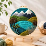 Finished snowy mountains and summer hills needle felting displayed on a wooden easel