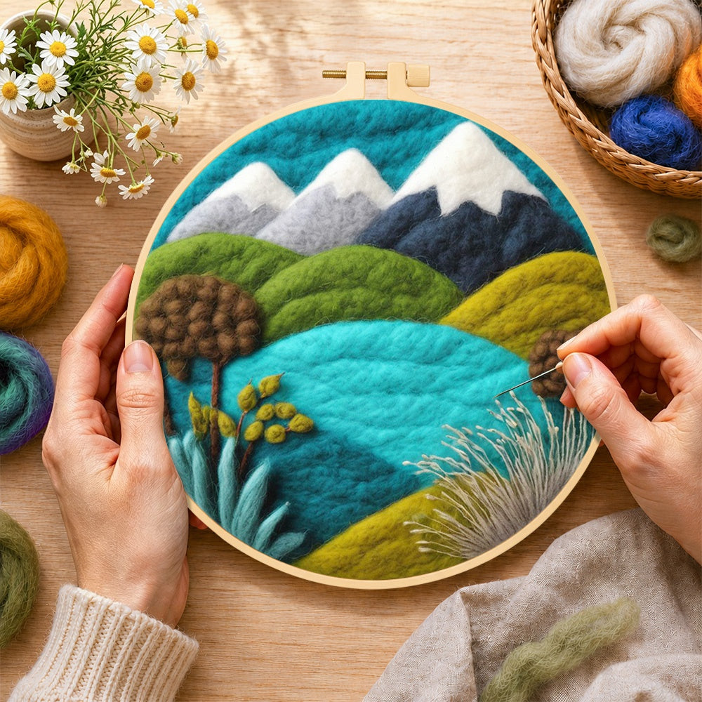 Creating the snowy mountains and summer hills wool painting by hand with a felting needle