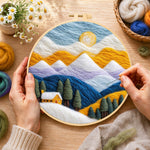 Creating the snowy peaks and yellow cottage with trees wool painting by hand with a felting needle