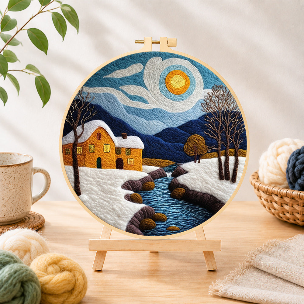 Finished snowy stream and yellow cottage needle felting displayed on a wooden easel