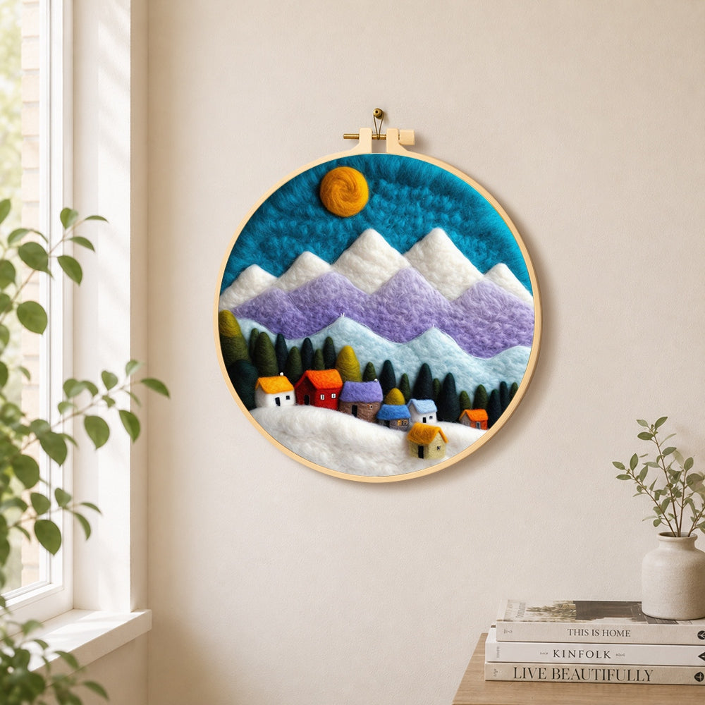 Snowy village under the mountains needle felt wall art displayed in a bright home interior