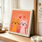 Snuggling orange and pink cat couple punch needle artwork displayed on a table