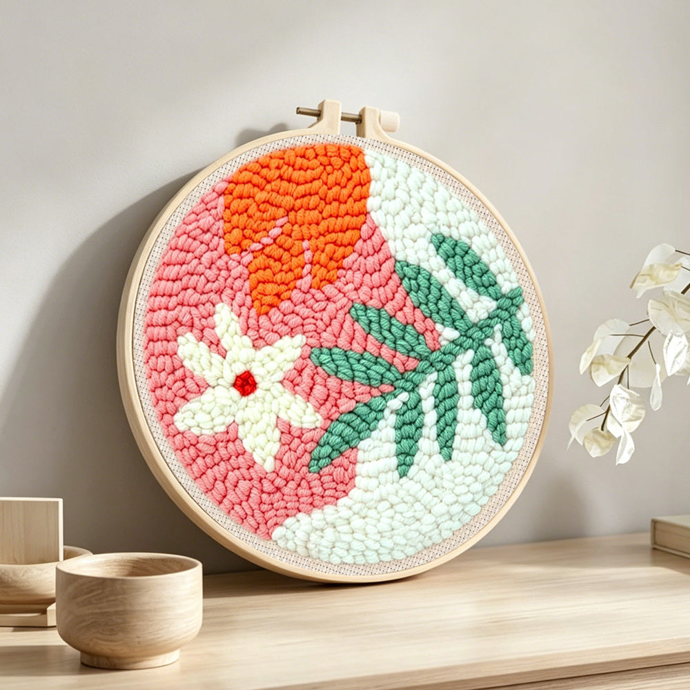 Soft green and orange botanical punch needle artwork displayed on a table