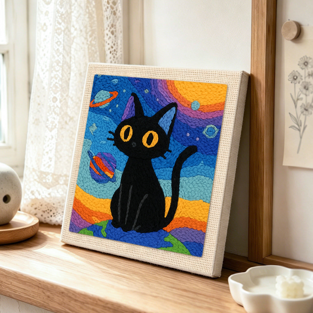 Space black cat with yellow eyes punch needle artwork displayed on a table