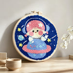 Space girl sitting on a planet punch needle artwork displayed on a table