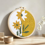 Split-tone dandelion flower punch needle artwork displayed on a table
