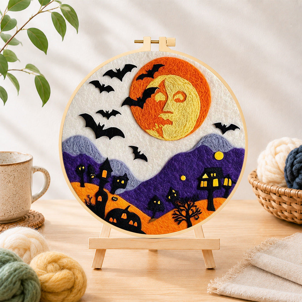 Finished spooky orange face moon and bats needle felting displayed on a wooden easel