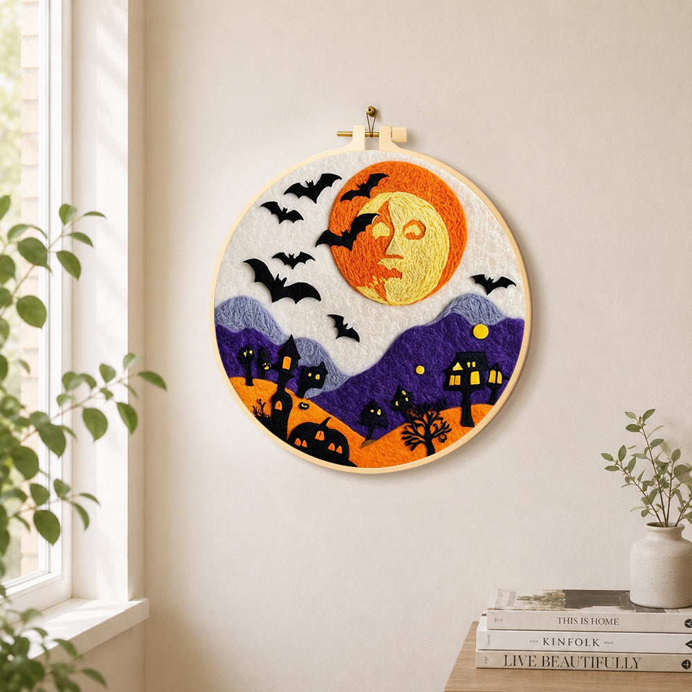 Spooky orange face moon and bats needle felt wall art displayed in a bright home interior