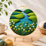 Finished spring river and green flowers needle felting displayed on a wooden easel