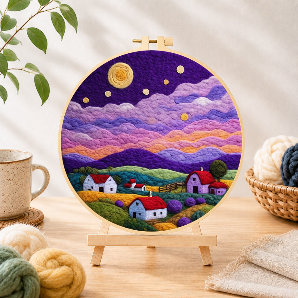 Finished starlit purple mountain village needle felting displayed on a wooden easel