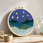 Starry mountain night landscape punch needle artwork displayed on a table