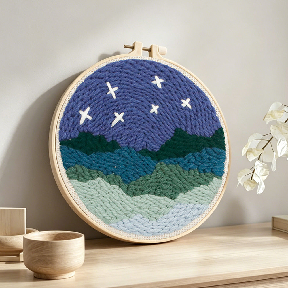 Starry mountain night landscape punch needle artwork displayed on a table