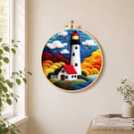 Starry night lighthouse and cottage needle felt wall art displayed in a bright home interior