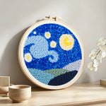 Starry night sky with moon and mountains punch needle artwork displayed on a table