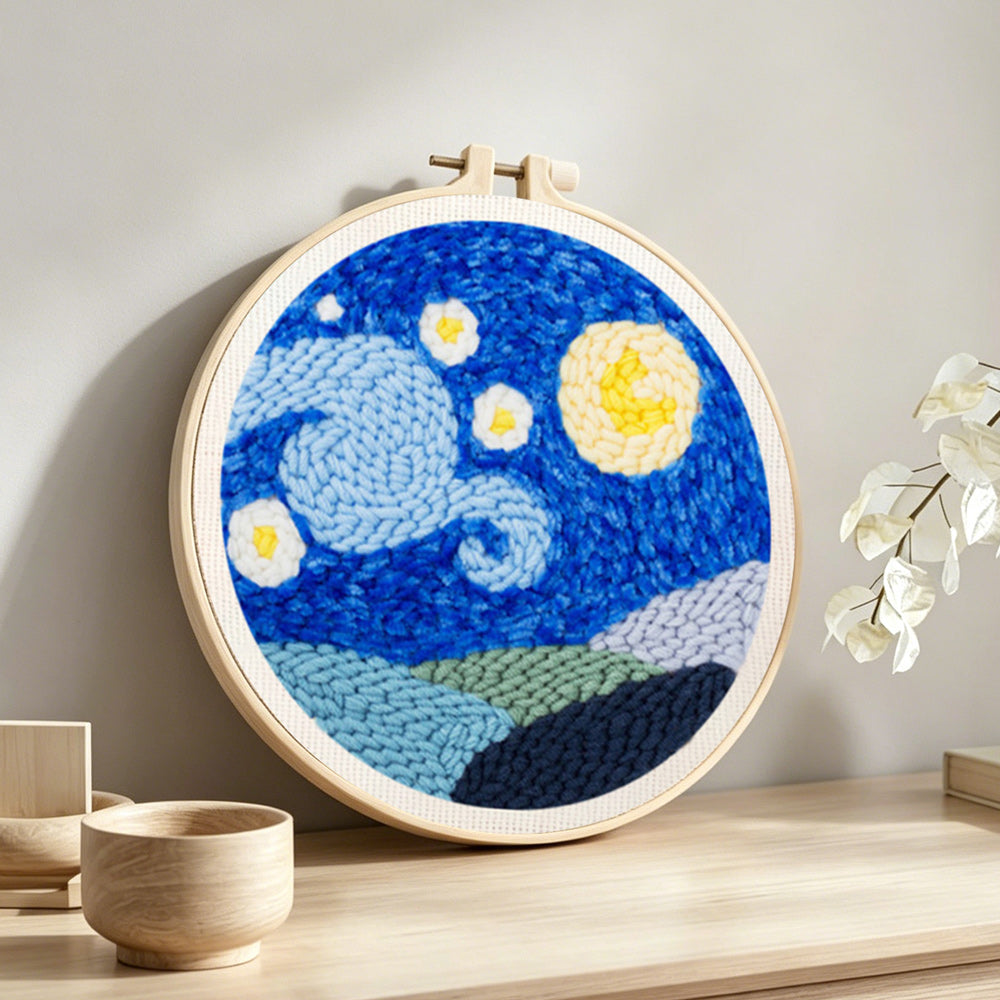 Starry night sky with moon and mountains punch needle artwork displayed on a table