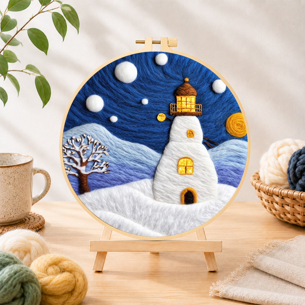 Finished starry night snowy lighthouse needle felting displayed on a wooden easel