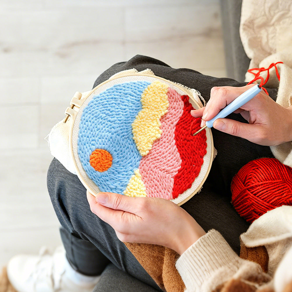 Creating handmade sun over colourful mountains and clouds punch needle artwork