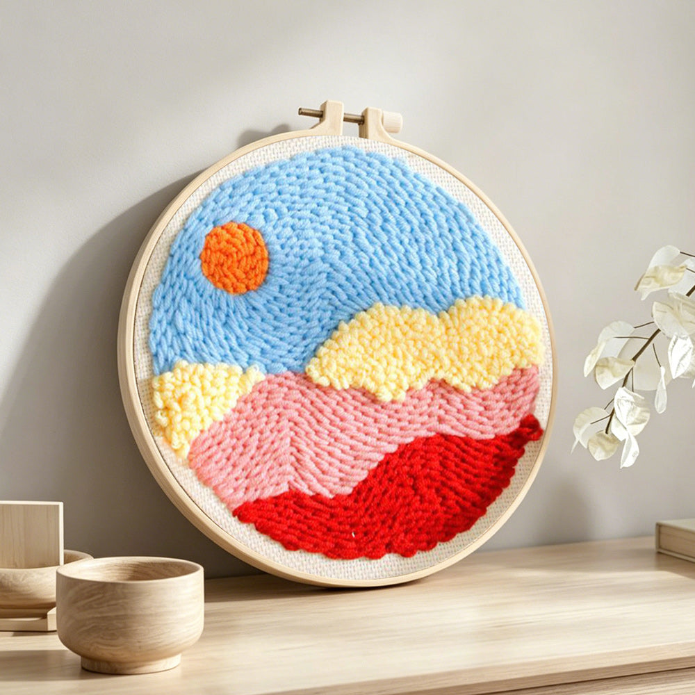 Sun over colourful mountains and clouds punch needle artwork displayed on a table