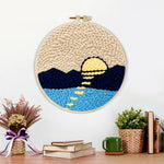 Finished sun over mountains and water artwork displayed on a wall