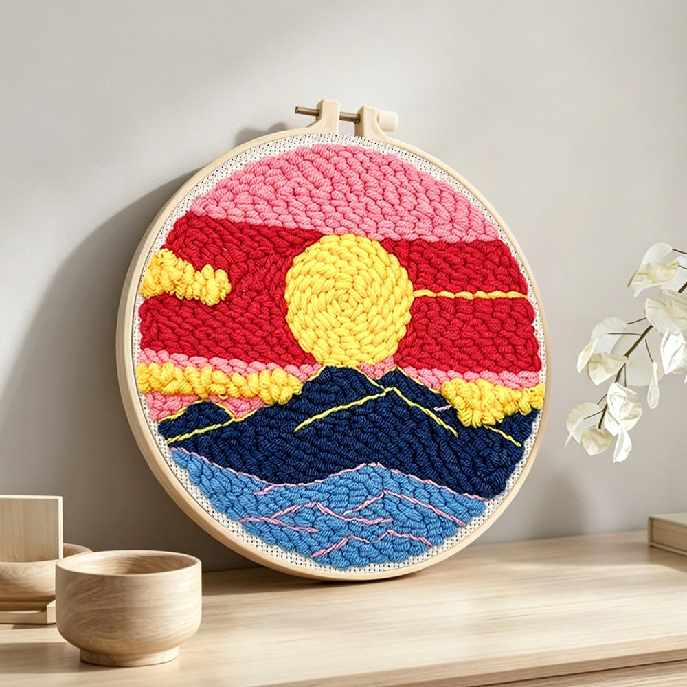 Finished sun over mountains with pink and red sky artwork displayed on a wall