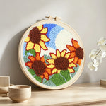 Sunflowers under blue sky punch needle artwork displayed on a table