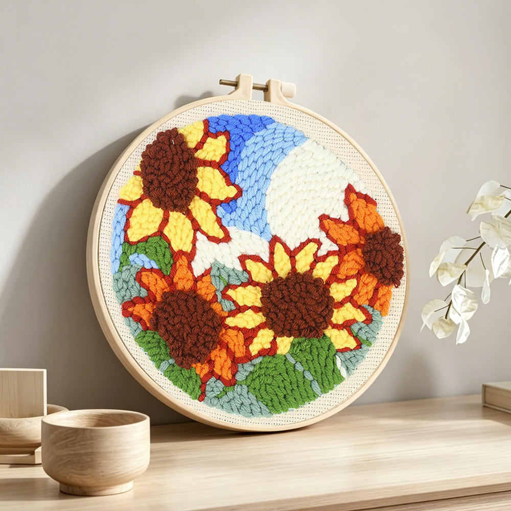 Sunflowers under blue sky punch needle artwork displayed on a table
