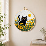 Sunny black cat in yellow flowers needle felt wall art displayed in a bright home interior