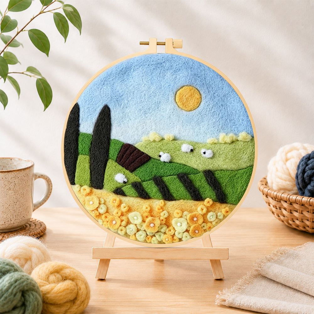 Finished sunny hillside and yellow flower field needle felting displayed on a wooden easel