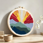 Sunrise mountain landscape punch needle artwork displayed on a table