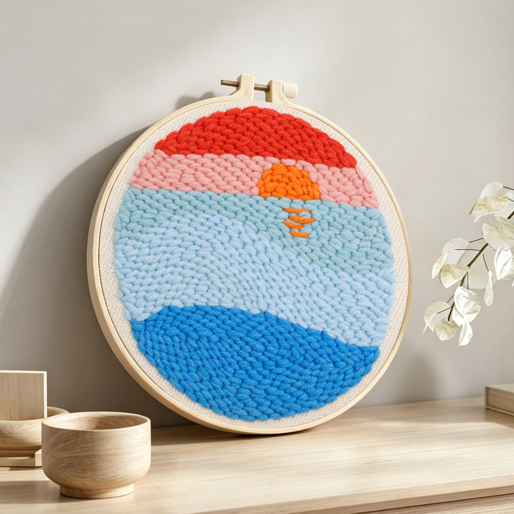 Sunrise over ocean punch needle artwork displayed on a table