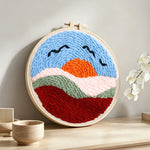 Sunset mountains and birds punch needle artwork displayed on a table