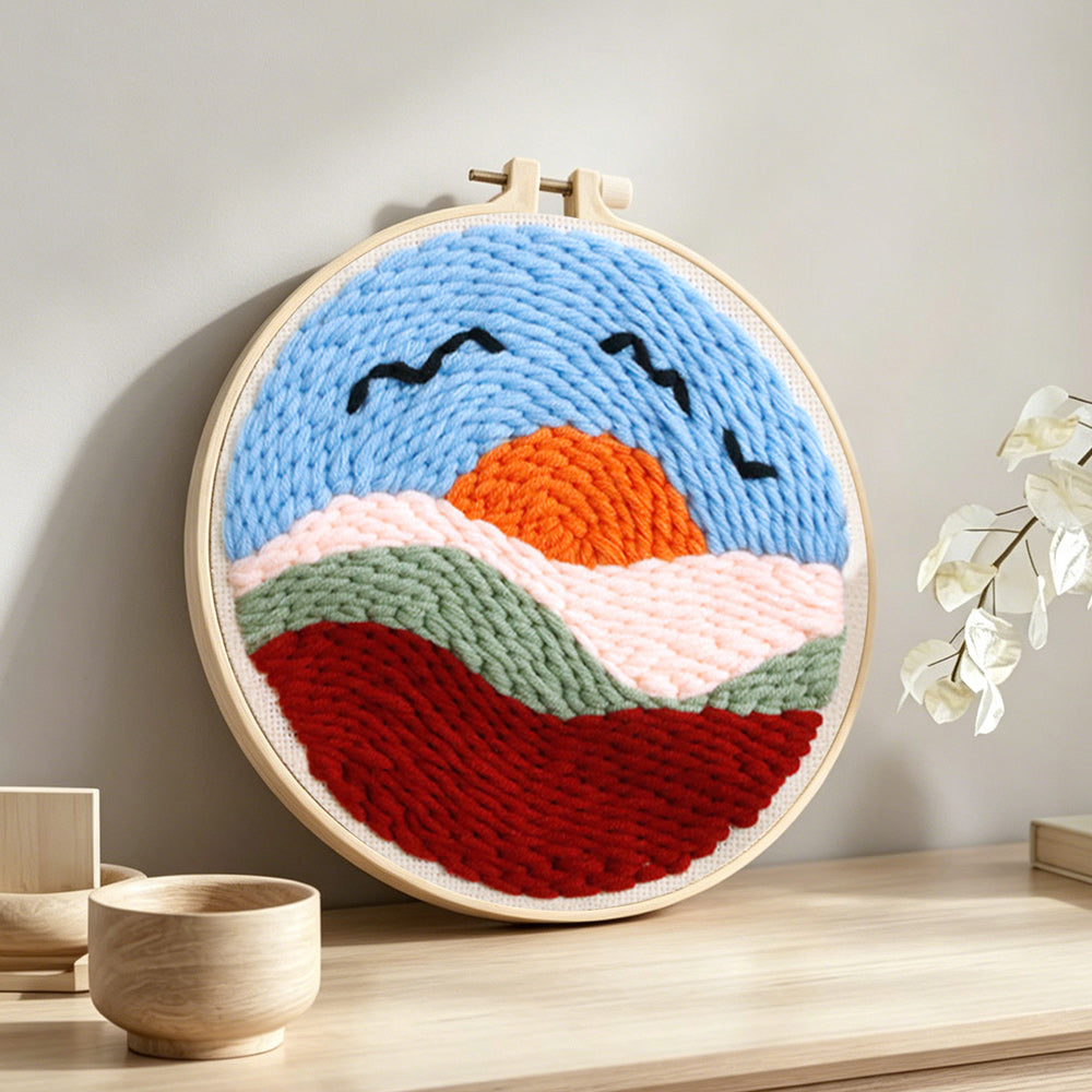 Sunset mountains and birds punch needle artwork displayed on a table
