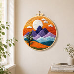 Sunset purple mountains and green sprig needle felt wall art displayed in a bright home interior