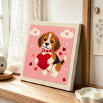 Sweet beagle puppy holding a big heart punch needle artwork displayed on a table