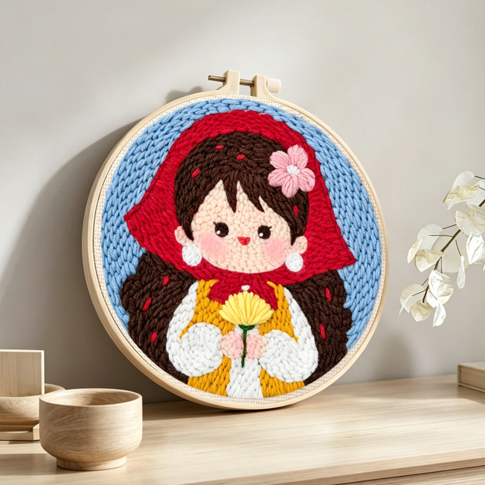 Sweet girl in red scarf holding flowers punch needle artwork displayed on a table