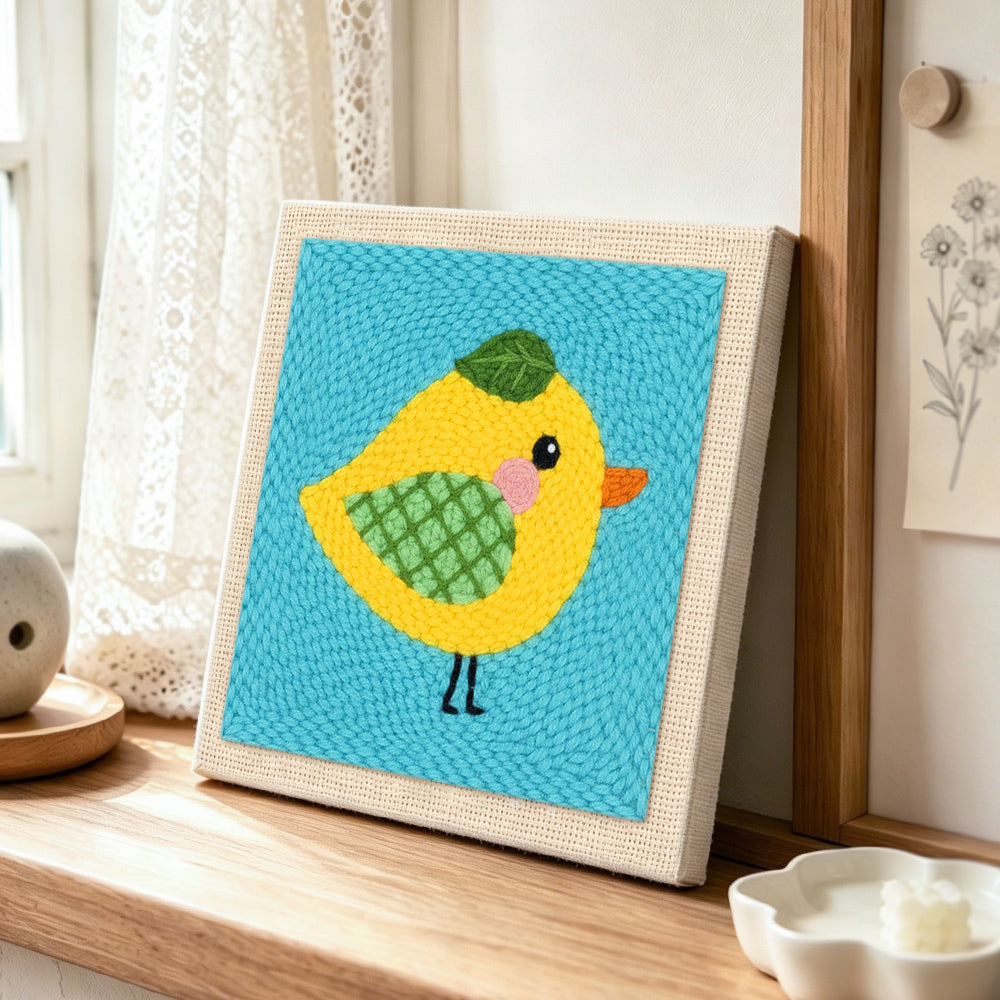 Sweet little yellow bird with green wing punch needle artwork displayed on a table