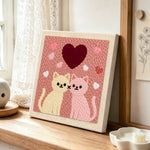 Sweet pink and cream cat pair with large heart punch needle artwork displayed on a table