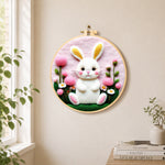Sweet white bunny and pink flowers needle felt wall art displayed in a bright home interior