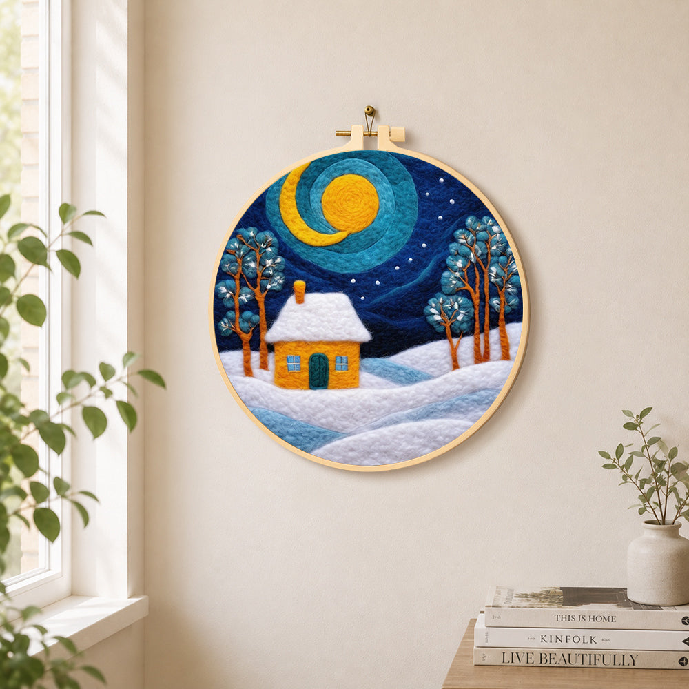 Swirling blue sky and yellow snowy cottage needle felt wall art displayed in a bright home interior