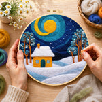 Creating the swirling blue sky and yellow snowy cottage wool painting by hand with a felting needle