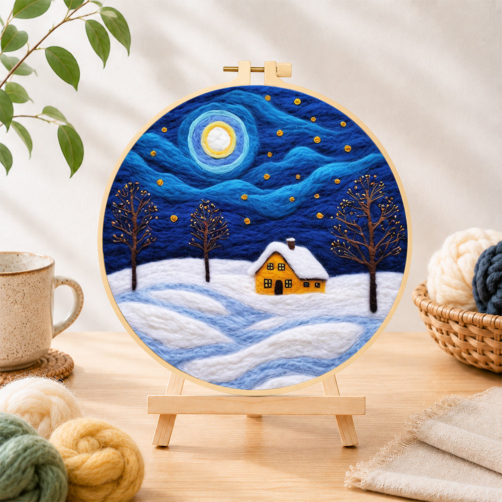 Finished swirling starry night and snowy cottage needle felting displayed on a wooden easel