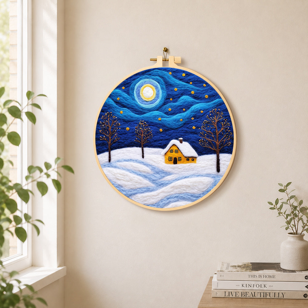 Swirling starry night and snowy cottage needle felt wall art displayed in a bright home interior