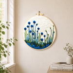 Tall blue wildflowers on white needle felt wall art displayed in a bright home interior