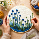 Creating the tall blue wildflowers on white wool painting by hand with a felting needle