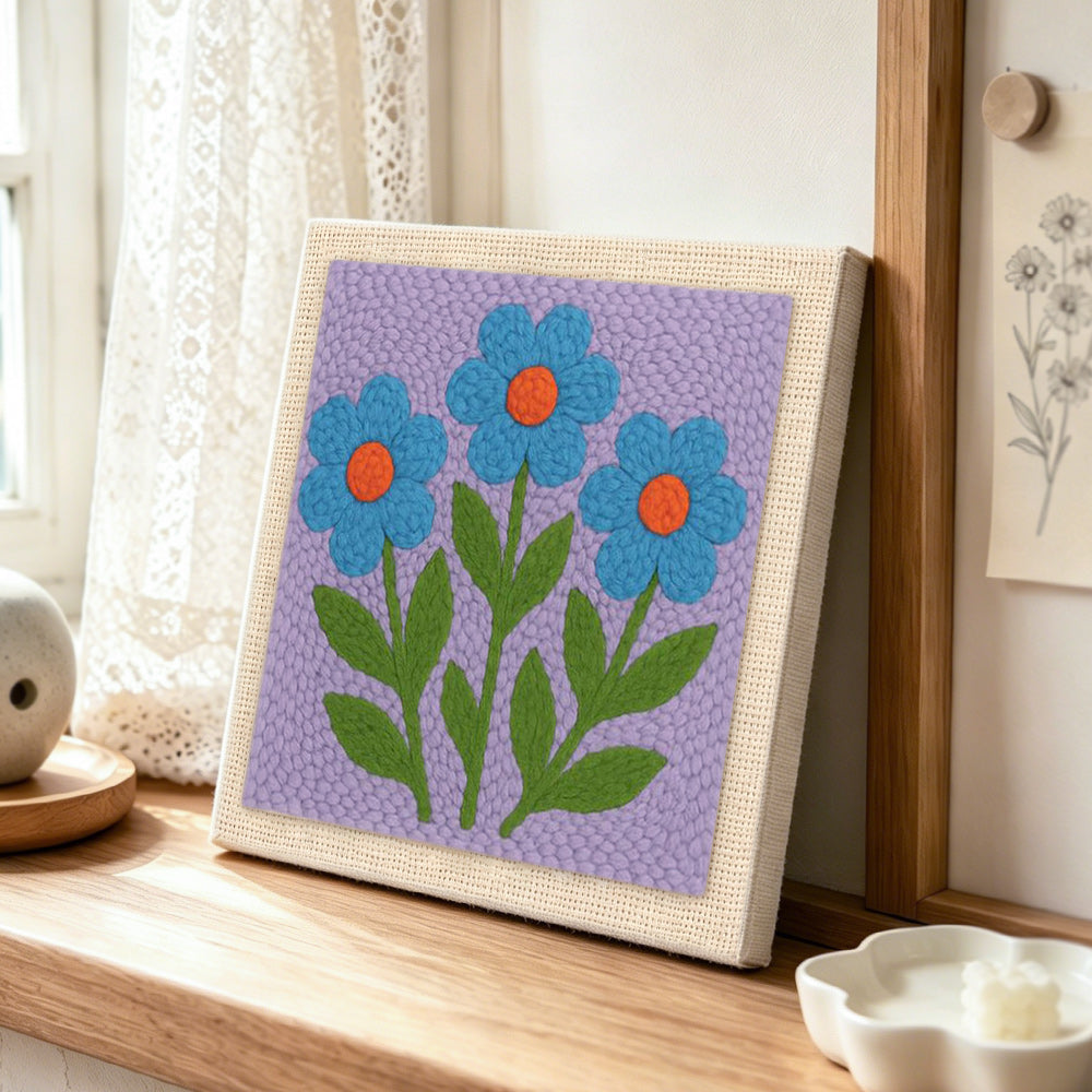 Three blue flowers punch needle artwork displayed on a table